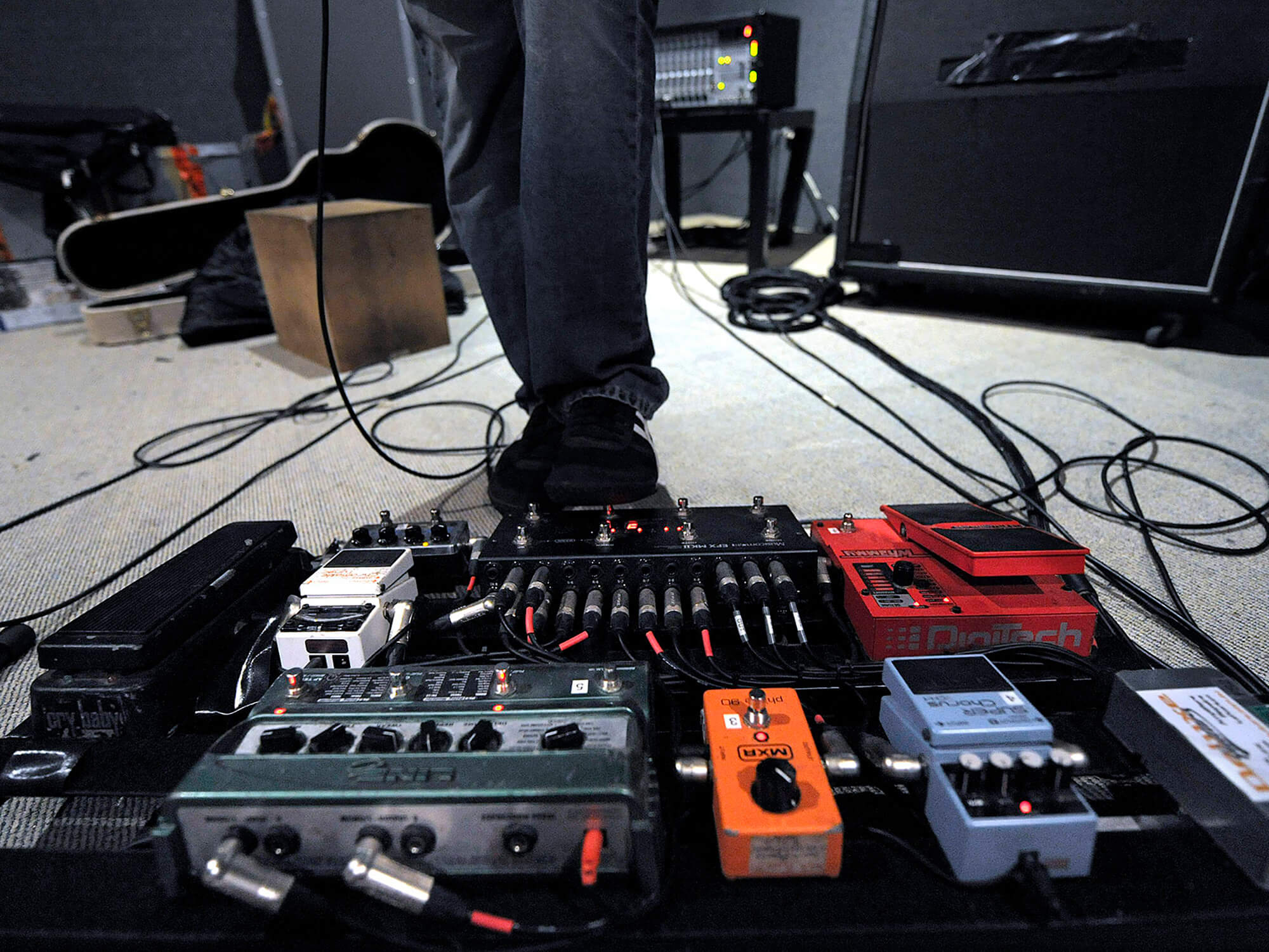 A guitarist operating a rack of guitar effects pedals